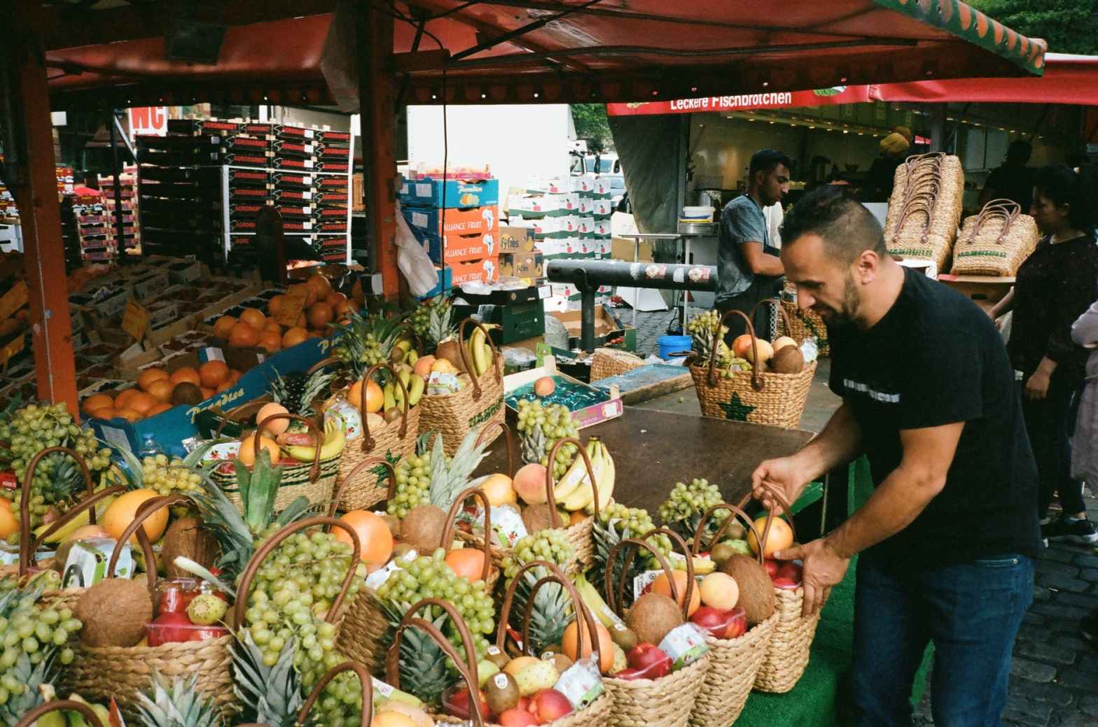 Man fixing basket of fruits on table a local market.
